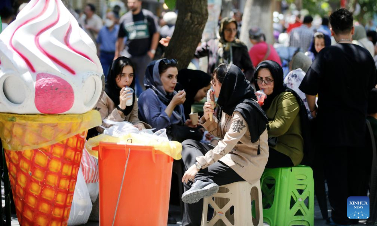People eat ice cream on a street in Tehran, Iran, July 22, 2025. Unrelenting high temperatures have triggered water and electricity shortages across large parts of Iran, with several cities issuing yellow weather alerts, Iranian media reported on Monday. (Xinhua)