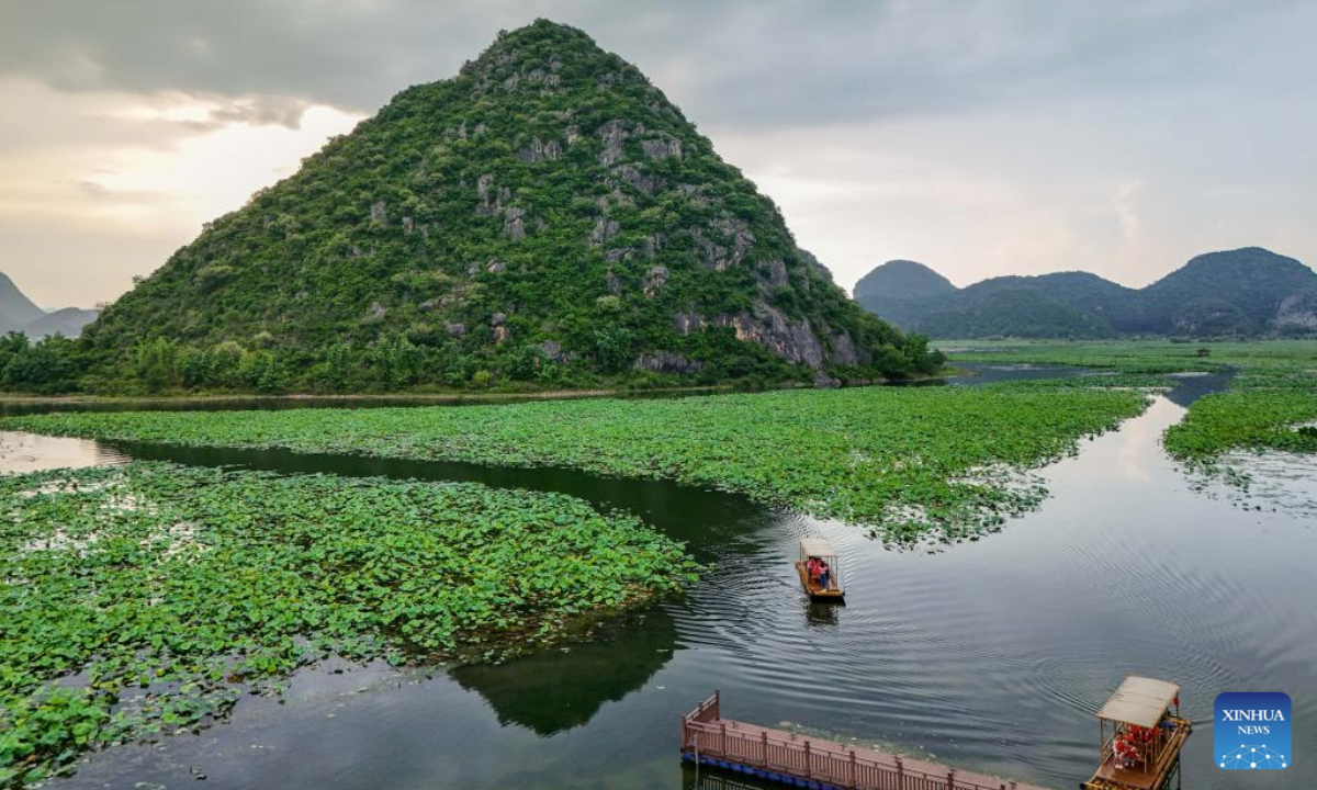 A drone photo taken on July 15, 2025 shows tourists taking a boat at the Puzhehei scenic area in Qiubei County, Wenshan Zhuang and Miao Autonomous Prefecture, southwest China's Yunnan Province. The beautiful scenery of Puzhehei, along with the rich amusement facilities there, has attracted lots of visitors during the summer. (Photo by Peng Yikai/Xinhua)
