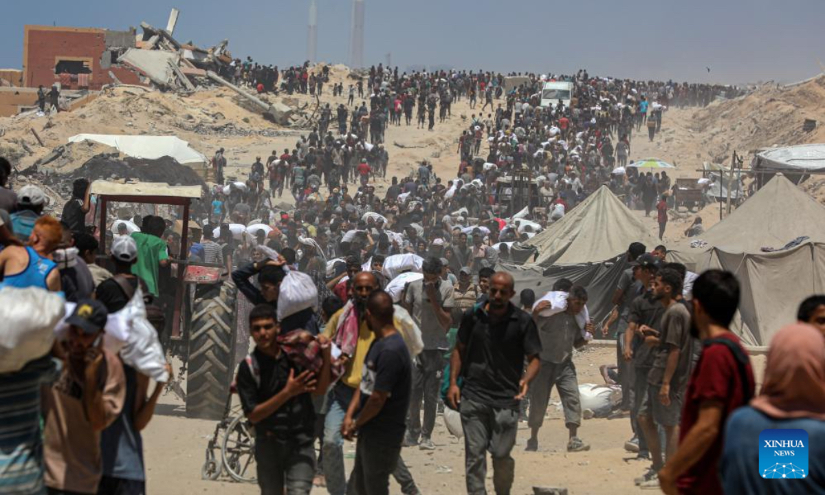 Palestinians carry humanitarian aid in Beit Lahia, northern Gaza Strip, on Aug. 1, 2025. (Photo by Rizek Abdeljawad/Xinhua)