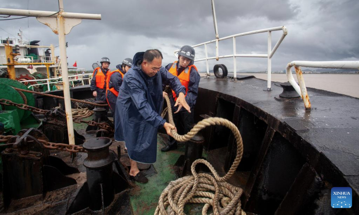 Police officers work with crew members to secure a mooring vessel at Sanjiangkou Wharf in Taizhou, east China's Zhejiang Province, July 7, 2025. China's Ministry of Water Resources on Monday activated a Level-IV emergency response to flooding in the eastern provinces of Zhejiang and Fujian as Typhoon Danas approaches. (Photo by Yu Yuexiang/Xinhua)