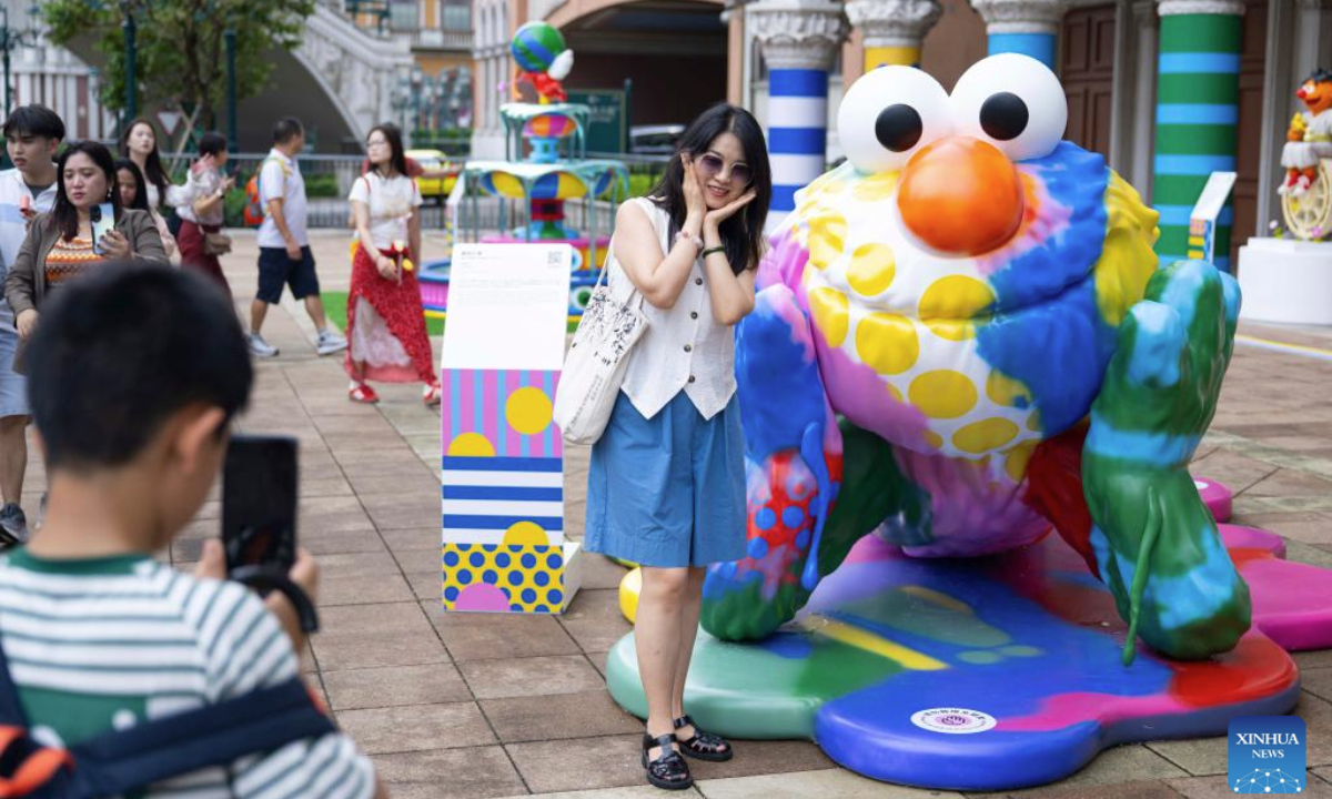 A tourist poses for a photo with an artwork on display during the special exhibition Dopamine: Fountain of Happiness at the Venetian Macao in Macao, south China, July 29, 2025. As a special exhibition of Art Macao: Macao International Art Biennale 2025, the event kicked off here on Tuesday. (Xinhua/Cheong Kam Ka)