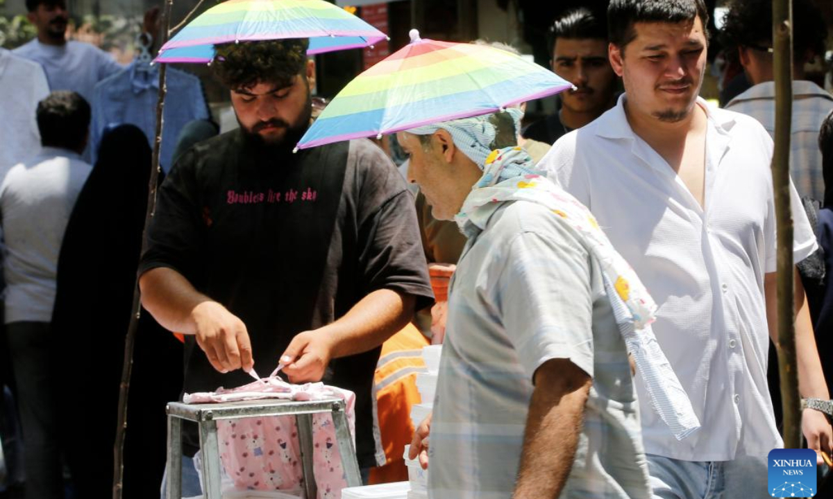People eat ice cream on a street in Tehran, Iran, July 22, 2025. Unrelenting high temperatures have triggered water and electricity shortages across large parts of Iran, with several cities issuing yellow weather alerts, Iranian media reported on Monday. (Xinhua)