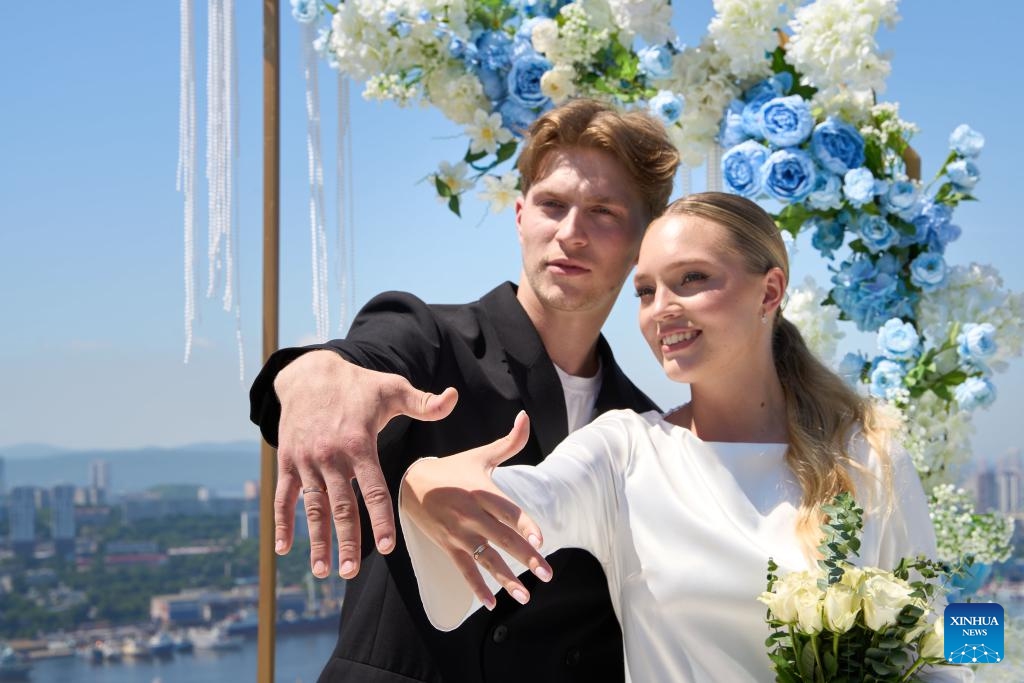 A couple shows off their wedding rings on a group wedding ceremony at Highland Park in Vladivostok, Russia, July 5, 2025. Three newlywed couples join in a group wedding ceremony here on Thursday, receiving blessings from families and friends. (Photo: Xinhua)