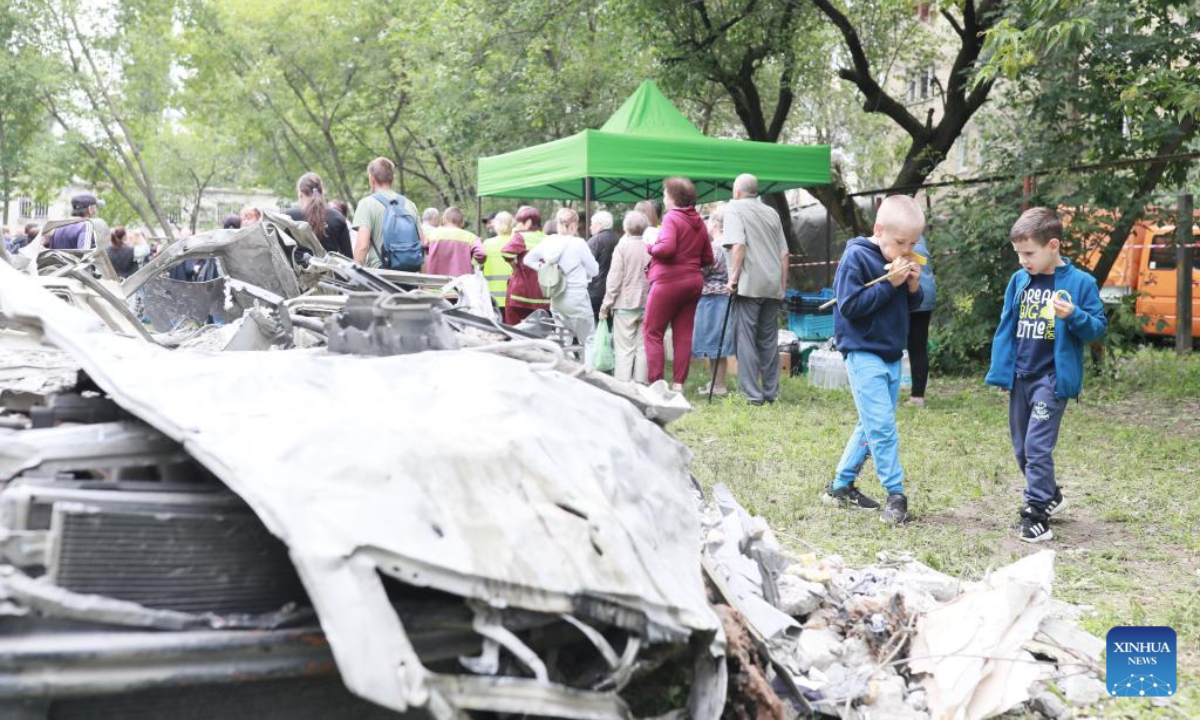 People are seen near the wreckage of vehicles after a Russian attack in the Sviatoshinskyi District of Kiev, Ukraine, on July 31, 2025. (Xinhua/Li Dongxu)