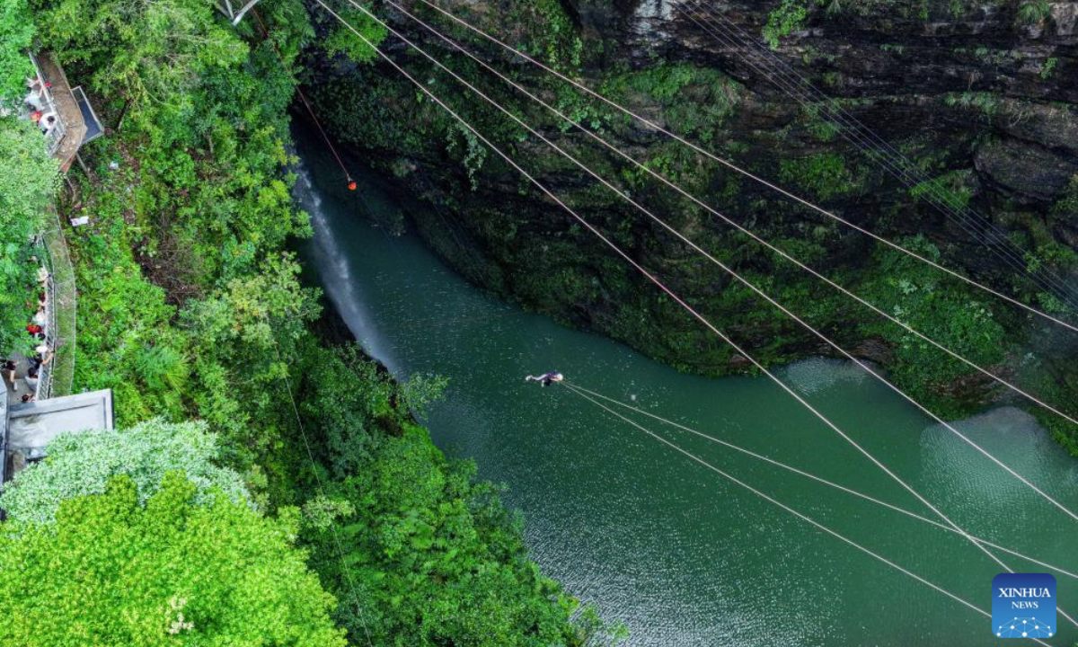 An aerial drone photo taken on July 22, 2025 shows a tourist playing a super giant swing in a giant sinkhole in Kaiyang County, southwest China's Guizhou Province. Guizhou Province is renowned for its extensive karst landscape, which is distinguished by its numerous giant sinkholes, locally called tiankeng or heavenly pits. The natural sinkholes are increasingly recognized for their unique tourism values. (Xinhua/Ou Dongqu)