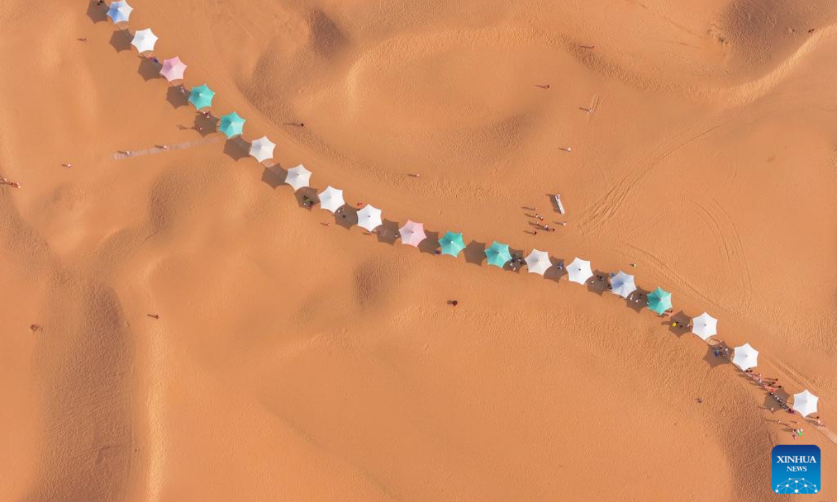 An aerial drone photo taken on Aug. 1, 2025 shows a view of a desert scenic area in Dalad Banner of Erdos City, north China's Inner Mongolia Autonomous Region. Kubuqi desert in Erdos City has entered its peak tourist season in midsummer, attracting numerous tourists from around the country to visit. (Xinhua/Lian Zhen)