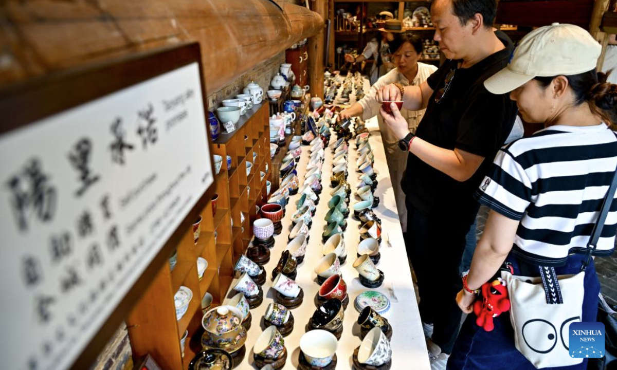 Tourists shop for handmade ceramic products in Taoyangli historical and cultural block in Jingdezhen City, east China's Jiangxi Province, July 13, 2025. Located in the heart of Jingdezhen, Taoyangli has successfully transformed from an old district into a thriving hub for cultural innovation and tourism in recent years. Today, it has become a must-visit destination for tourists. (Xinhua/Liu Jinhai)