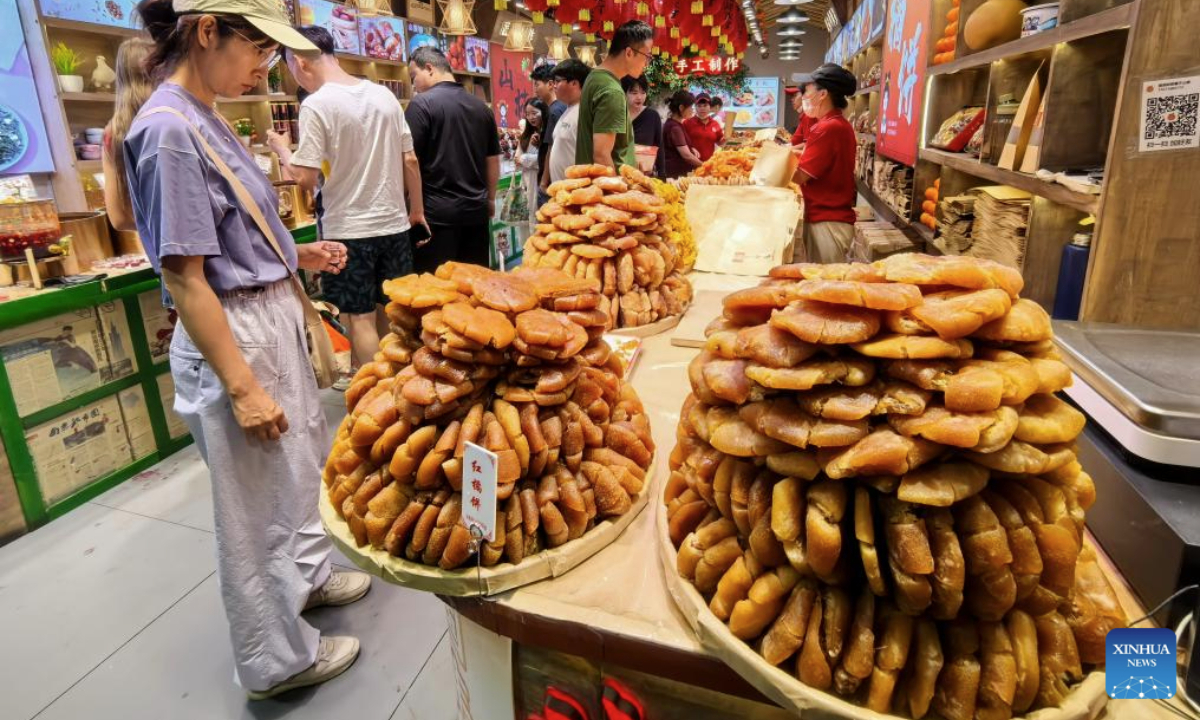 People select snacks in a store at Gulou street in Beijing, capital of China, July 30, 2025. Beijing has vigorously developed its night economy since the beginning of this summer, featuring local cuisine, outdoor films, music festivals, and night markets. (Xinhua/Li Xin)