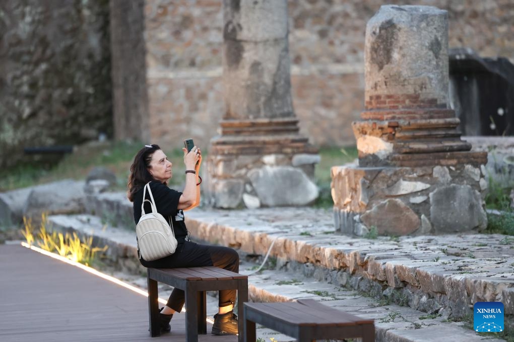 A woman takes photos during a night tour at the Imperial Forum in Rome, Italy, July 5, 2025. The Imperial Forum has opened to visitors on every Friday, Saturday and Sunday evening since June 20 and will last until September 28. (Photo: Xinhua)