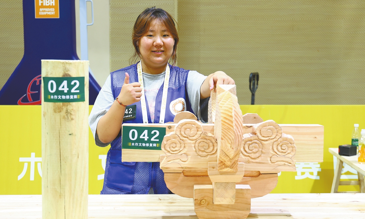 Zhang Yue shows off her complex dougong carving, a roof-support system of wooden brackets commonly found in traditional Chinese architecture, during the competition. Photo: Courtesy of National Cultural Heritage Administration