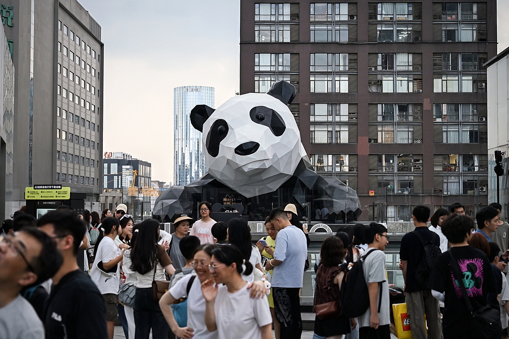 Tourists take photos with a wall-climbing giant panda sculpture on Chengdu's Chunxi Road, Southwest China's Sichuan Province, on July 10, 2025. Popular scenic spots, boasting a vibrant mix of shopping, dining, and cultural experiences, are bustling with visitors from both China and abroad during the summer vacation. As the 2025 summer travel season commenced on July 1 and extends through August 31, China's tourism sector is gearing up for a remarkable boom. 
Photo: VGC