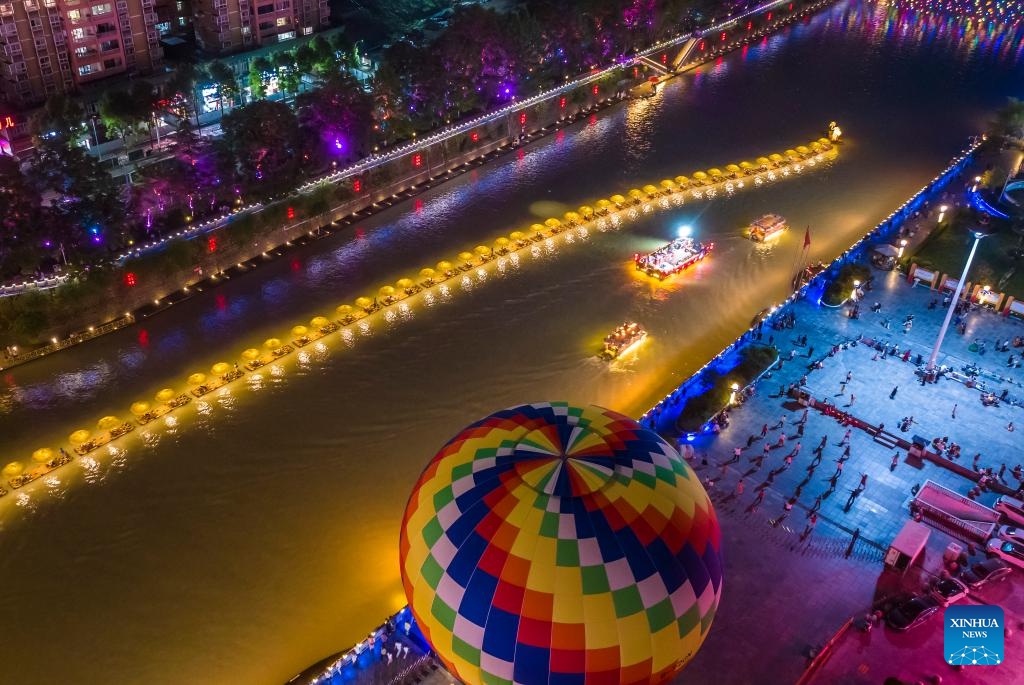 An aerial drone photo taken on July 9, 2025 shows tourists enjoying a night view in Xuan'en County, Enshi Tujia and Miao Autonomous Prefecture, central China's Hubei Province. In recent years, Xuan'en County of central China's Hubei Province has promoted nighttime tourism around the Gongshui River, which runs through the county. Activities and shows ranging from bamboo raft rides to molten iron fireworks attract visitors to enjoy the charm of the county under the lights. (Photo: Xinhua)