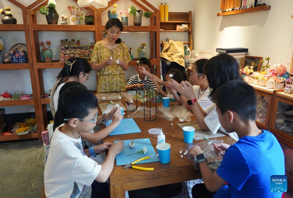 Children make handicrafts in Diaoyuan Ancient Village of Ji'an, east China's Jiangxi Province, July 9, 2025. Tucked into the undulating hills of Ji'an City in east China's Jiangxi Province, Diaoyuan Village has stood for over 1,100 years -- the layout from above bearing a striking resemblance to a Taoist Tai Chi diagram. Since 2021, the local government has introduced social capital for the comprehensive cultural and tourism development of the ancient village, aiming to enhance operational efficiency and service quality. (Photo: Xinhua)