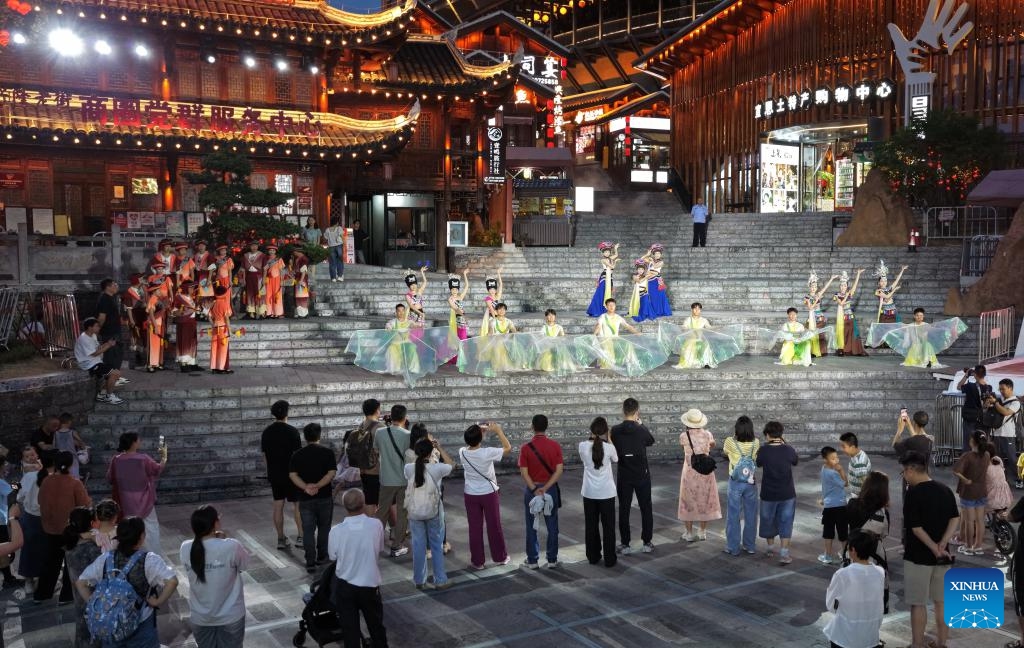 A drone photo taken on July 9, 2025 shows tourists watching a performance in Xuan'en County, Enshi Tujia and Miao Autonomous Prefecture, central China's Hubei Province. In recent years, Xuan'en County of central China's Hubei Province has promoted nighttime tourism around the Gongshui River, which runs through the county. Activities and shows ranging from bamboo raft rides to molten iron fireworks attract visitors to enjoy the charm of the county under the lights. (Photo: Xinhua)