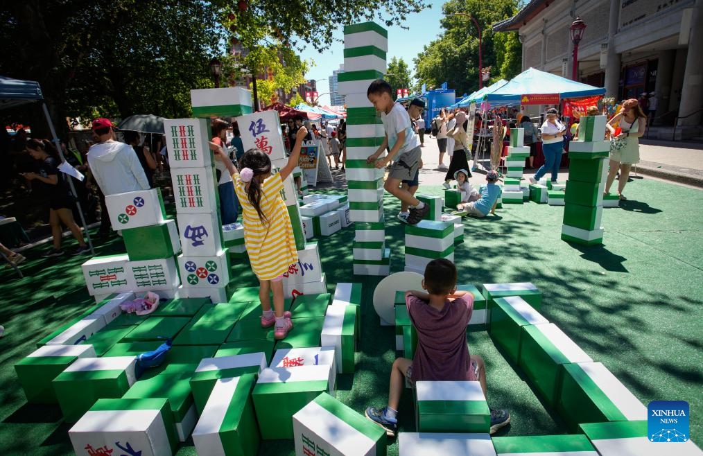 Children play with oversized mahjong tiles during the 23rd Vancouver Chinatown Festival in Vancouver, British Columbia, Canada, July 13, 2025. The annual cultural festival was held in Vancouver's historic Chinatown, celebrating Chinese heritage and promoting multiculturalism through performances, food stalls, exhibits, and family-friendly activities. (Photo: Xinhua)