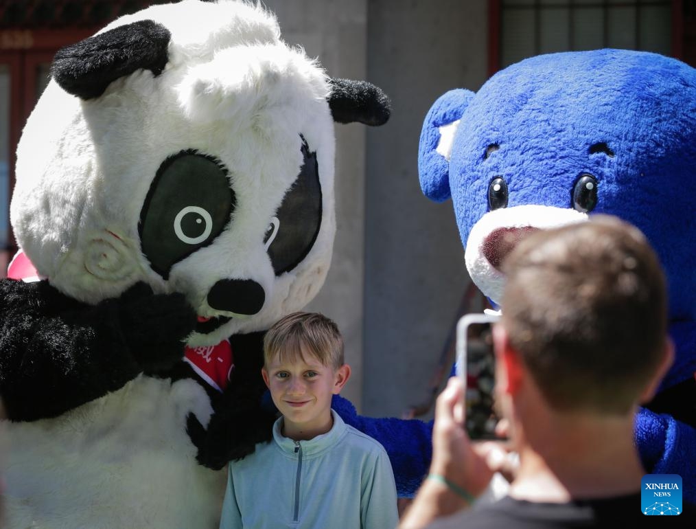 A boy takes photos with the mascots of the 23rd Vancouver Chinatown Festival in Vancouver, British Columbia, Canada, July 13, 2025. The annual cultural festival was held in Vancouver's historic Chinatown, celebrating Chinese heritage and promoting multiculturalism through performances, food stalls, exhibits, and family-friendly activities. (Photo: Xinhua)