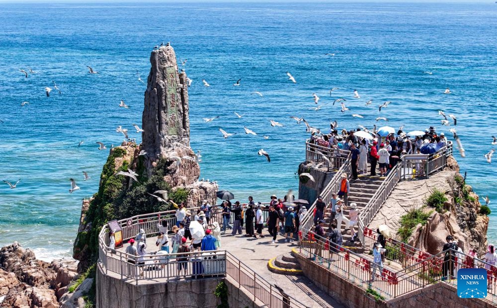 An aerial drone photo taken on July 12, 2025 shows visitors interacting with gulls at a scenic spot in Rongcheng City, east China's Shandong Province. With heatwaves hitting some Chinese provinces and regions in recent days, the scorching temperature has fueled a cooling economy boom. (Photo: Xinhua)