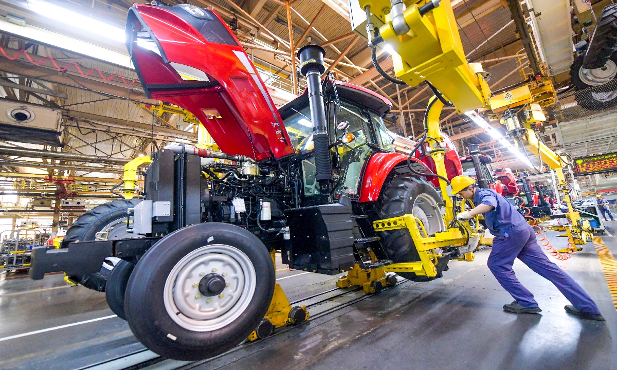Workers assemble a tractor from the 