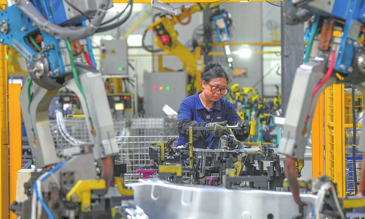 An employee, together with intelligent machines, processes orders for new-energy vehicle (NEV) components at an auto manufacturing company in Jinhua, East China's Zhejiang Province on July 16, 2025. The company supplies parts to NEV manufacturers, with an annual output of 700,000 units. Photo: VCG