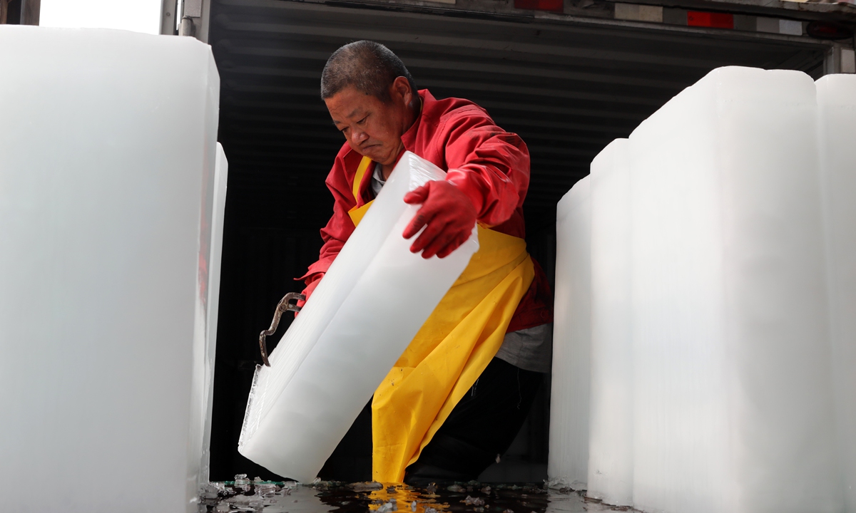 A worker at an ice factory in Anyang, Central China's Henan Province, carries 25-plus-kilogram ice blocks onto a transport vehicle on July 17, 2025. Amid persistent high temperatures, the factory's ice blocks are selling fast. Photo: VCG
