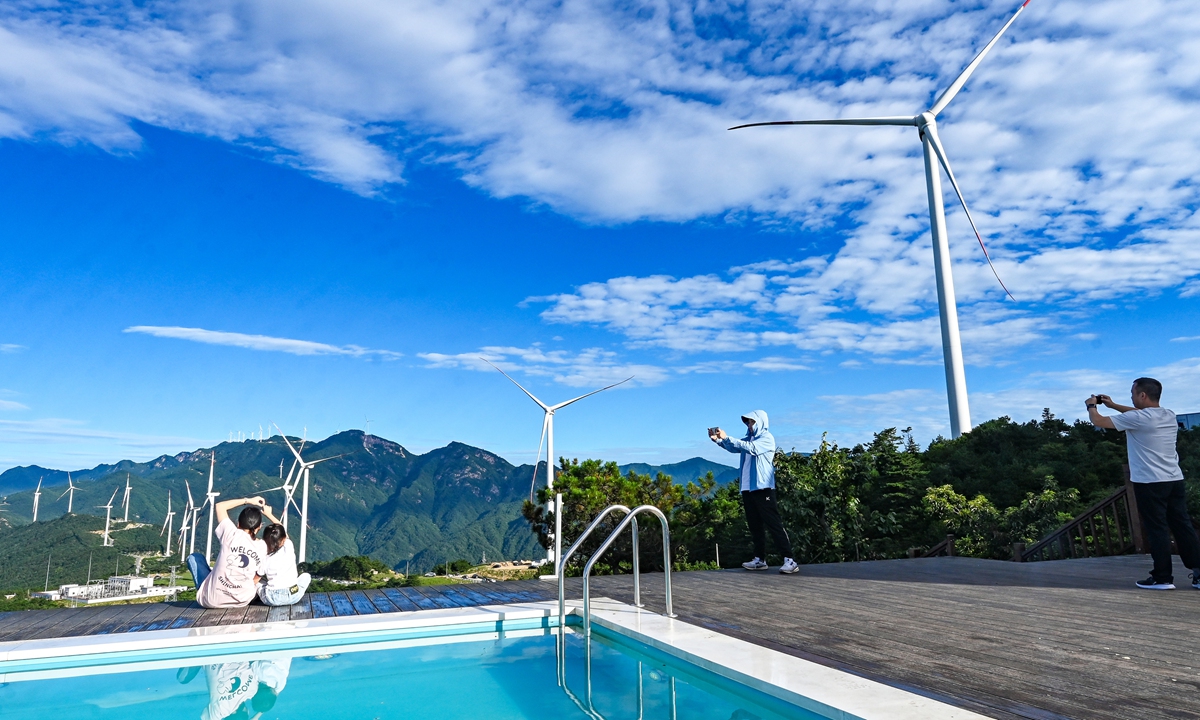 Tourists take photos from hilltops where a wind farm occupies mountain ridges in Yuexi county of Anqing, East China's Anhui Province on July 20, 2025. In the first three months of this year, 707 million visitors took part in rural tourism in China, up 8.9 percent year-on-year, official data from Ministry of Culture and Tourism showed. Photo: VCG
