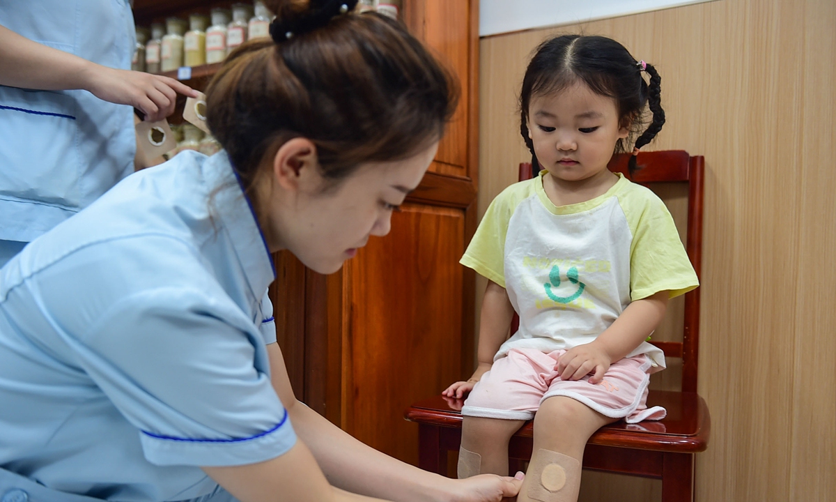 A medical staff member in Cangzhou, North China's Hebei Province applies the Sanfutie  treatment to a child on July 20, 2025. The Sanfutie is a procedure in traditional Chinese medicine in which medicated patches are placed on various acupuncture points on the body. The sanfu period, or 