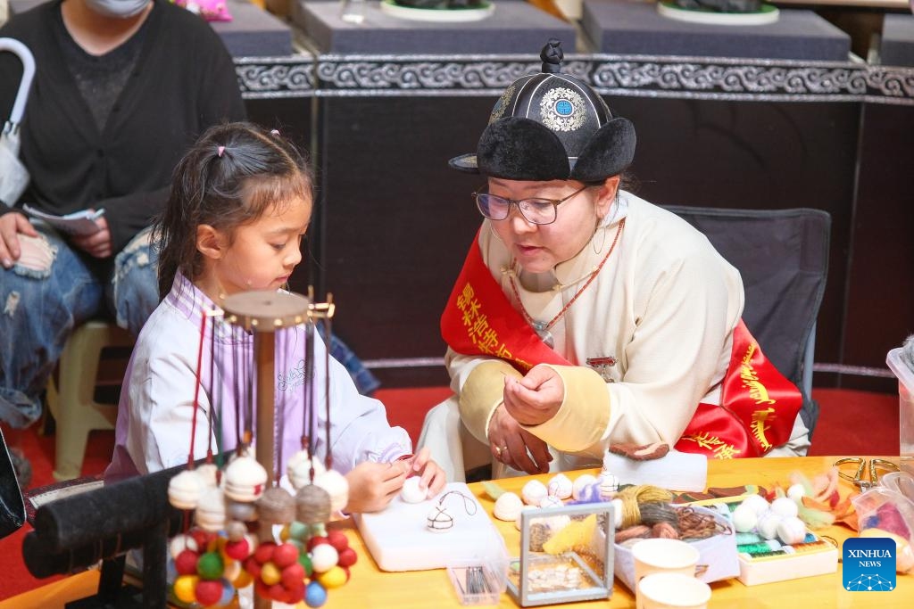 A kid experiences the traditional Mongolian felt making during a Nadam fair held in Xilinhot, Xilin Gol League, north China's Inner Mongolia Autonomous Region, July 19, 2025. The Nadam Fair opened here on Saturday, featuring night parade performances, intangible cultural heritage handicraft making events, and ethnic game experiences. The fair has effectively invigorated the summer tourism market, and attracted tourists to experience the charm of grassland culture. (Photo: Xinhua)