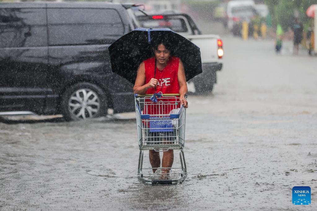 A man pushes a shopping cart through a waterlogged road in Quezon City, the Philippines, on July 19, 2025. Wipha intensified into a severe tropical storm as it blew away from the Philippines on Saturday, bringing strong winds and heavy rains to many areas. (Photo: Xinhua)