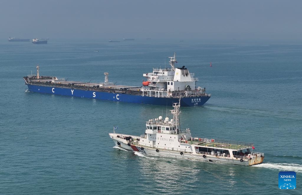 A drone photo taken on July 18, 2025 shows a patrol vessel (front) escorting a departing cargo ship in the waters of Caofeidian Port Area in Tangshan Port in Tangshan, north China's Hebei Province. The cargo throughput at Tangshan Port reached 433.56 million tonnes in the first half of 2025, up 0.75 percent year on year, according to port authorities.  (Photo: Xinhua)