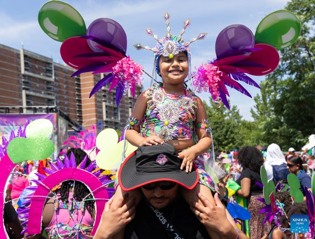 A dressed-up girl sitting on her father's shoulders participates in the Junior Carnival Parade of the 2025 Toronto Caribbean Carnival in Toronto, Canada, on July 19, 2025. The annual event kicked off here on Saturday with thousands of young participants in vibrant costumes celebrating Caribbean culture with music and dance. (Photo: Xinhua)