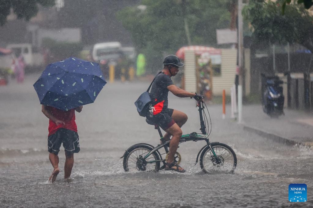 People move through a waterlogged road in Quezon City, the Philippines, on July 19, 2025. Wipha intensified into a severe tropical storm as it blew away from the Philippines on Saturday, bringing strong winds and heavy rains to many areas. (Photo: Xinhua)