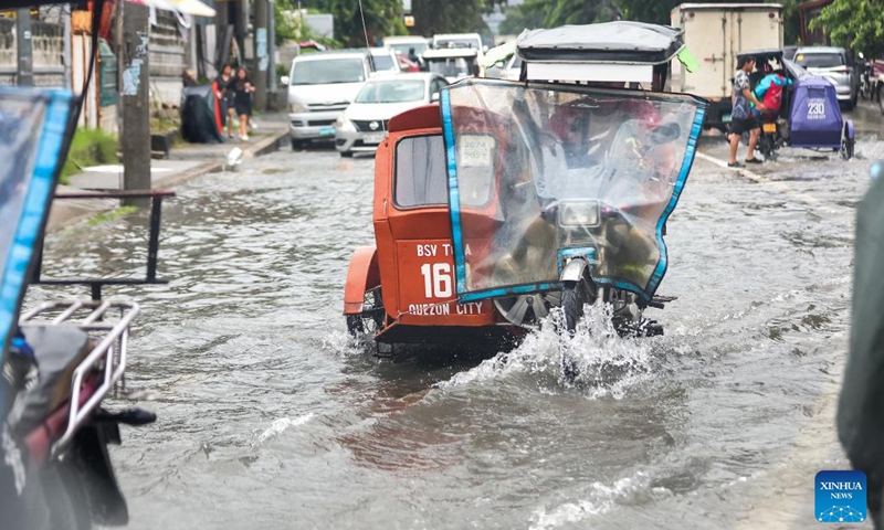 Vehicles move through a waterlogged road in Quezon City, the Philippines, on July 19, 2025. Wipha intensified into a severe tropical storm as it blew away from the Philippines on Saturday, bringing strong winds and heavy rains to many areas. (Photo: Xinhua)