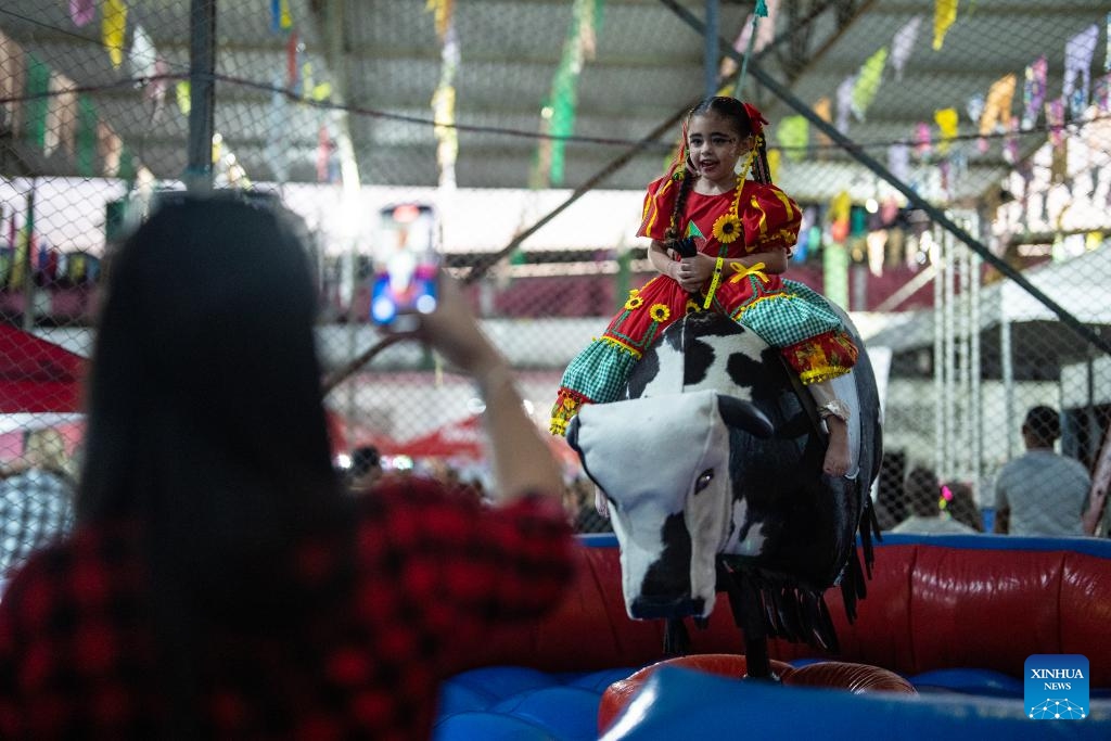 A girl rides a mechanical bull during a celebration of harvest in the Manguinhos community in Rio de Janeiro, Brazil, July 19, 2025. (Photo: Xinhua)