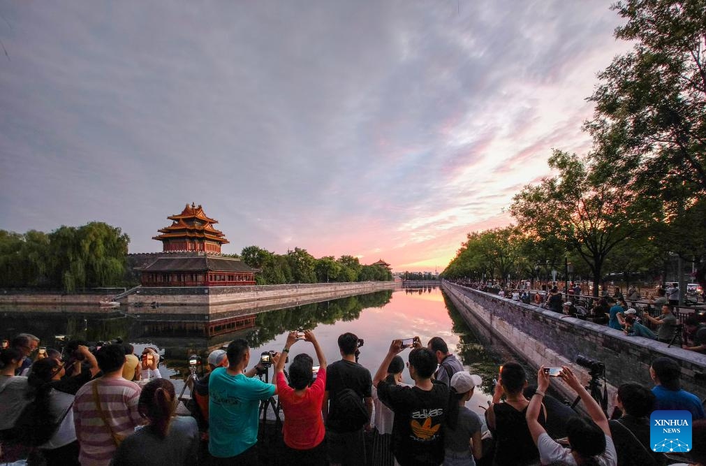 This photo taken by cell phone on July 20, 2025 shows people taking pictures of a turret of the Palace Museum in evening glow in Beijing, capital of China. (Photo:Xinhua)