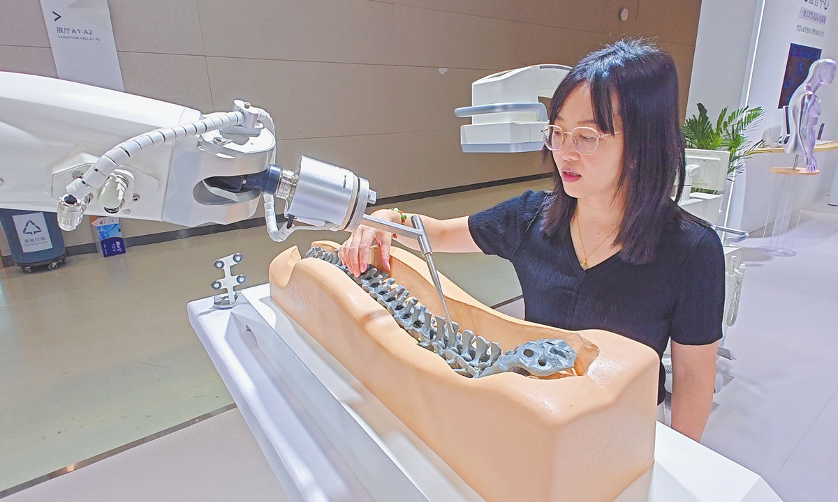 A visitor watches an integrated orthopedic surgical robot for spinal trauma on display at the 14th China International Service Outsourcing Expo, held at the China Optics Valley Convention and Exhibition Center in Wuhan, Central China's Hubei Province, on July 25, 2025. A wide range of cutting-edge products are being showcased at the event. 
Photo: VCG