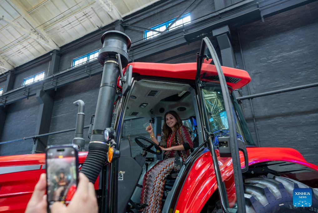 A participant of the Shanghai Cooperation Organization (SCO) Media and Think Tank Summit poses for photos at a tractor manufacturer in Luoyang, central China's Henan Province, July 26, 2025. The SCO Media and Think Tank Summit is held in Zhengzhou from July 23 to 27. Participants are invited to visit various locations in Henan during the summit. (Photo: Xinhua)