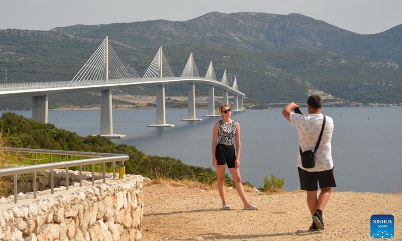 A woman poses for photos with the Peljesac Bridge in Komarna, Croatia on July 26, 2025. (Photo: Xinhua)