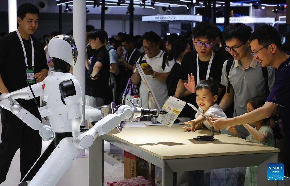 A child takes over a product he has purchased from a humanoid robot sales assistant at the exhibition area of the 2025 World AI Conference and High-Level Meeting on Global AI Governance in east China's Shanghai, July 26, 2025. The event kicked off here on Saturday. More than 1,000 officials and representatives of industries, universities and research institutes from home and abroad attended the opening ceremony. (Photo: Xinhua)