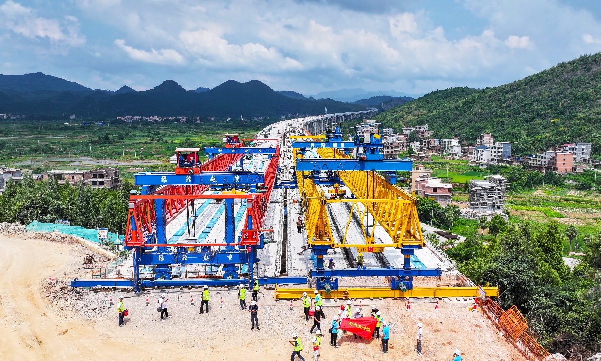 Workers stand in front of a section of the Guiyang-Xintian Expressway in Liujiaqiao Village, Xintian county, Yongzhou, Hunan Province on July 30, 2025. At 2,377.5 meters long, the expressway bridge was successfully connected on the day, becoming the longest elevated expressway bridge in southern Hunan. Photo: VCG