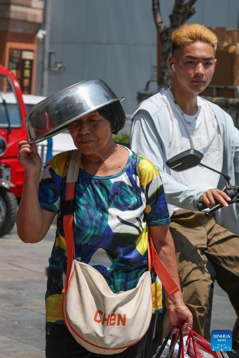 A woman shields herself from the sunshine with a basin in Jiangbei District, southwest China's Chongqing Municipality, Aug. 2, 2025. Chongqing issued a heatwave alert on Saturday, with high temperature hitting 40-43 degrees Celsius. Photo: Xinhua