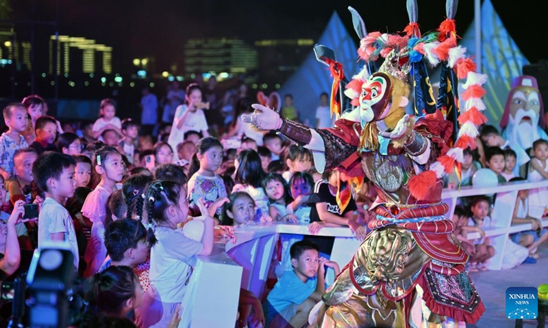 A performer interacts with kids at the opening ceremony of the 2025 (26th) Hainan Island Carnival in Haikou, south China's Hainan Province, Aug. 2, 2025. The 2025 (26th) Hainan Island Carnival kicked off on Saturday here. With various activities arranged across the island, the event will last till Aug. 31. Photo: Xinhua