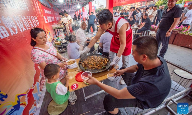 People enjoy Chaobola, a street food listed as municipal-level intangible cultural heritage, at a food festival in Zhangye, northwest China's Gansu Province, Aug. 2, 2025. Photo: Xinhua