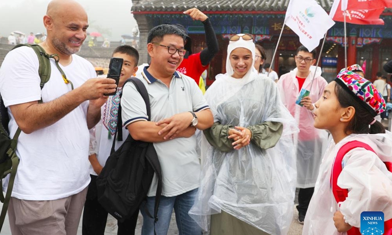 Patimanhan Parihat (R) communicates with foreign tourists and invites them to visit Xinjiang at the Badaling section of the Great Wall in Beijing, capital of China, July 28, 2025.