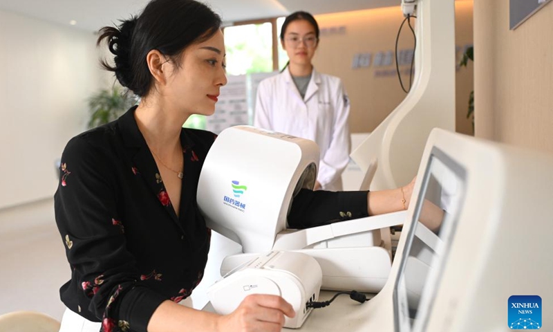 A woman measures blood pressure by herself at a smart health station of Meilin Village in Xiaoshan District of Hangzhou, east China's Zhejiang Province, on Aug. 4, 2025. Meilin, which has long been a model village for rural development, has been actively exploring ways to reduce pollution and carbon emissions in recent years. Through a series of measures such as promoting rooftop photovoltaic projects, building smart farmlands and integrated photovoltaic charging and storage stations, clean energy is being widely adopted here, injecting green impetus for the rural revitalization. (Xinhua/Mao Zhu)