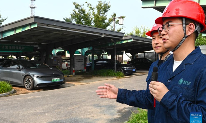 A technician introduces an integrated photovoltaic charging and storage station at Meilin Village in Xiaoshan District of Hangzhou, east China's Zhejiang Province, on Aug. 4, 2025. Meilin, which has long been a model village for rural development, has been actively exploring ways to reduce pollution and carbon emissions in recent years. Through a series of measures such as promoting rooftop photovoltaic projects, building smart farmlands and integrated photovoltaic charging and storage stations, clean energy is being widely adopted here, injecting green impetus for the rural revitalization. (Xinhua/Mao Zhu)