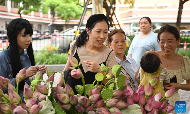 Tourists buy lotus flowers at a market by the West Lake scenic spot in Hangzhou, east China's Zhejiang Province, Aug. 3, 2025. (Xinhua/Mao Zhu)