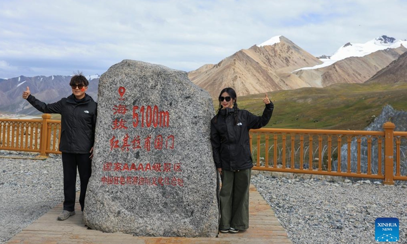 People pose for photos at the Khunjerab Pass, a land port on the China-Pakistan border, in Tajik Autonomous County of Taxkorgan, northwest China's Xinjiang Uygur Autonomous Region, Aug. 2, 2025. Tajik Autonomous County of Taxkorgan has entered the peak travel season as more tourists come here to experience the culture and enjoy the scenery on the plateau. (Xinhua/Wang Fei)