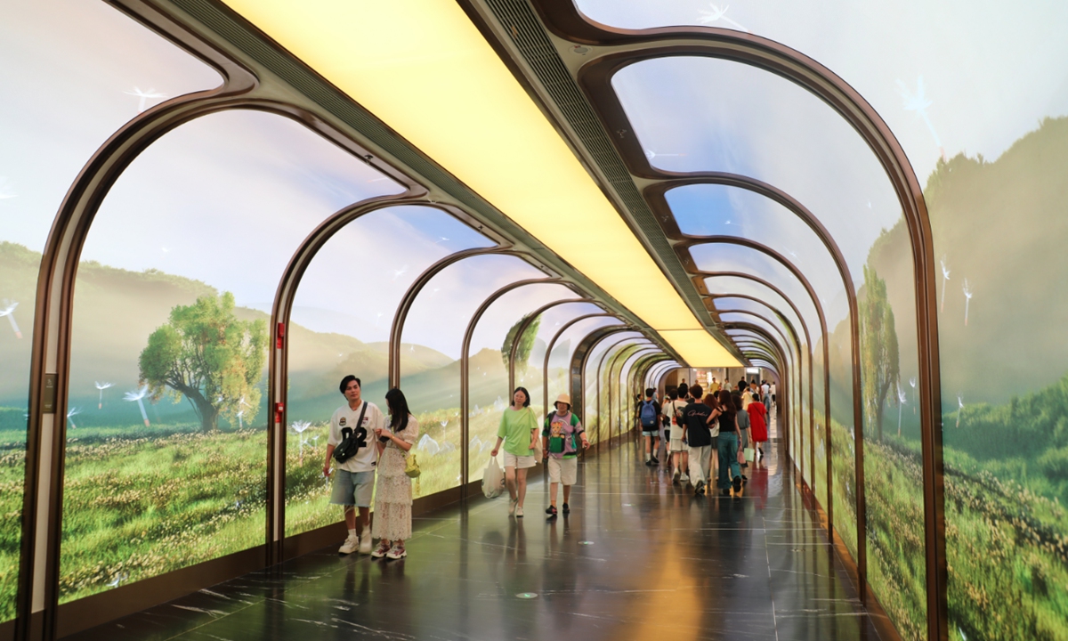 Citizens and tourists walk through the Time-Space Light and Shadow Corridor in the Xinjiekou business district in Nanjing, East China's Jiangsu Province, on August 7, 2025. The corridor features expansive glass curtain walls and curved structures, exuding a strong sense of technology and modern aesthetics, earning it the title of