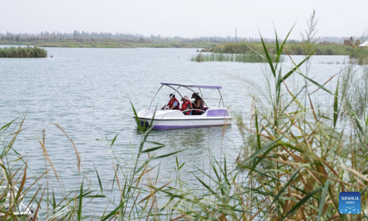 People take a boat at the Lalikun wetland nature reserve in Moyu County of Hotan Prefecture, northwest China's Xinjiang Uygur Autonomous Region, Aug. 6, 2025. In Xinjiang, new wetlands such as the Manas national wetland park and the Lalikun wetland nature reserve have emerged near the border of Gurbantunggut Desert and Taklimakan Desert, acting as important ecological shelters for migrant birds and safeguarding the biodiversity and oases in the region. (Xinhua/Zhou Jiayi)