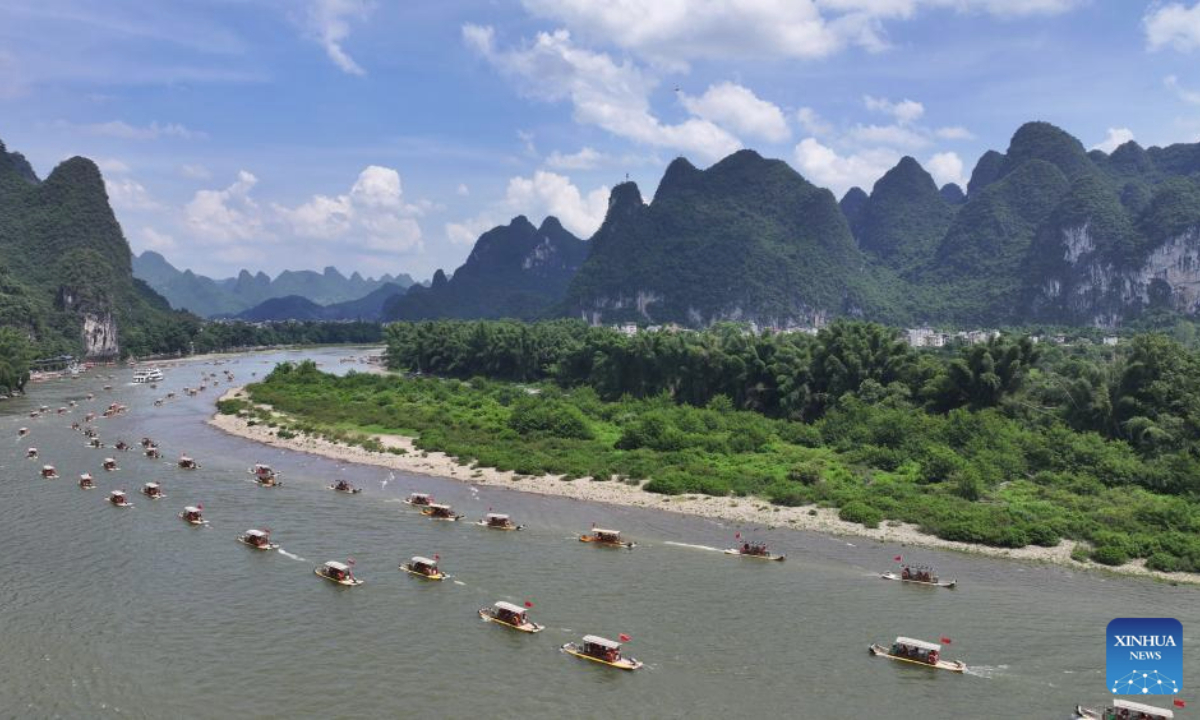 An aerial drone photo taken on Aug. 10, 2025 shows tourists enjoying the scenery on bamboo rafts along the Lijiang river in Yangshuo County, south China's Guangxi Zhuang Autonomous Region. Scenic areas across China have entered peak season for tourism during summer vacation. (Photo by He Hongfu/Xinhua)